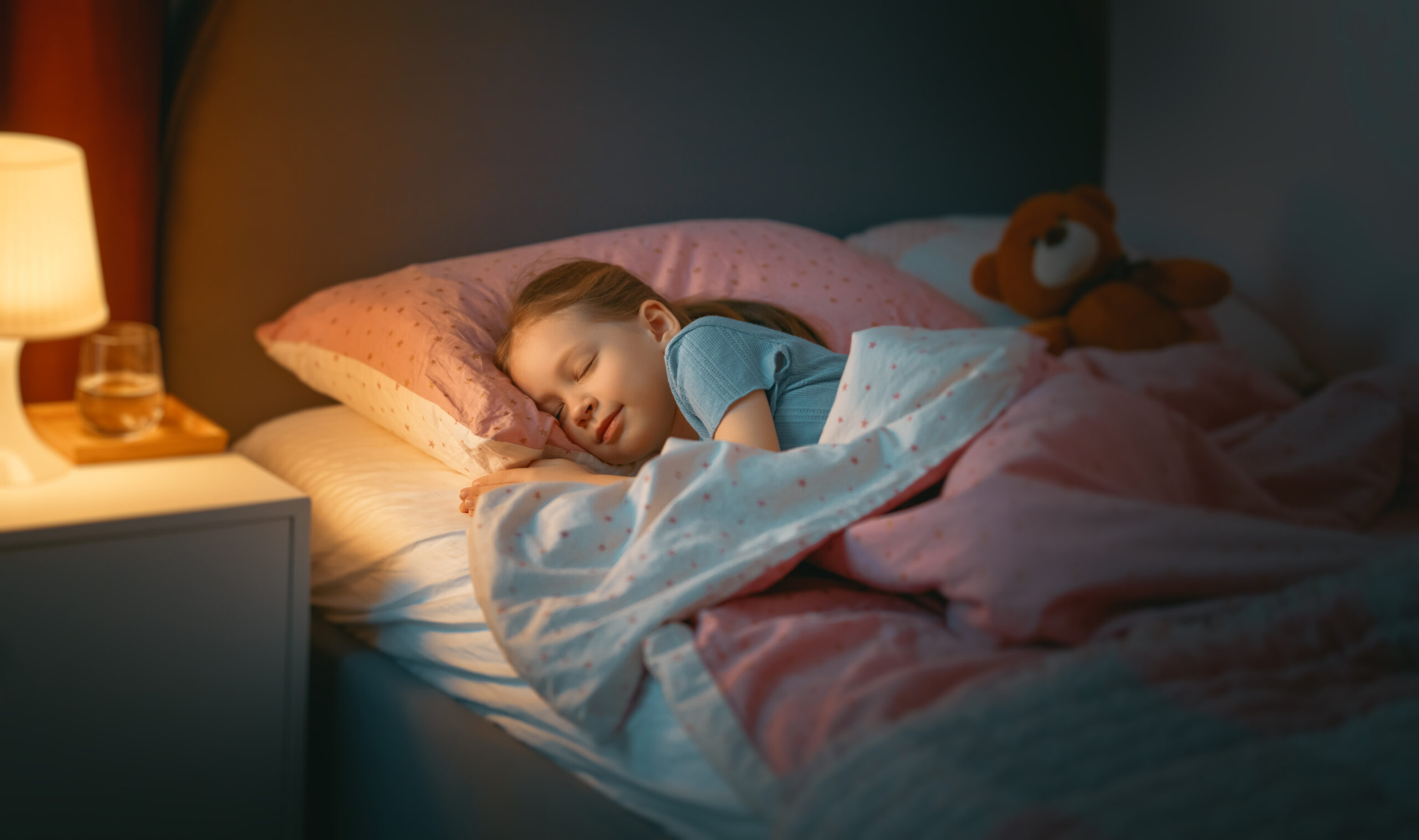 Adorable little child is sleeping in the bed.